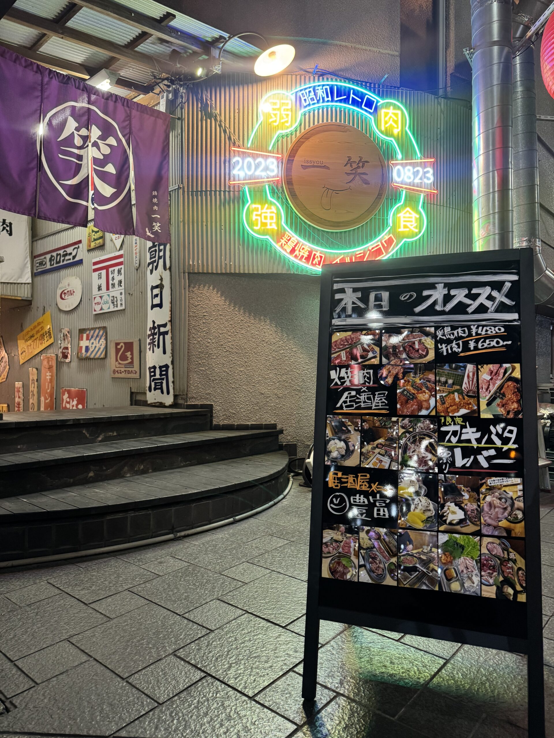 一笑の入口。紫ののれんとネオン看板、階段が目印です